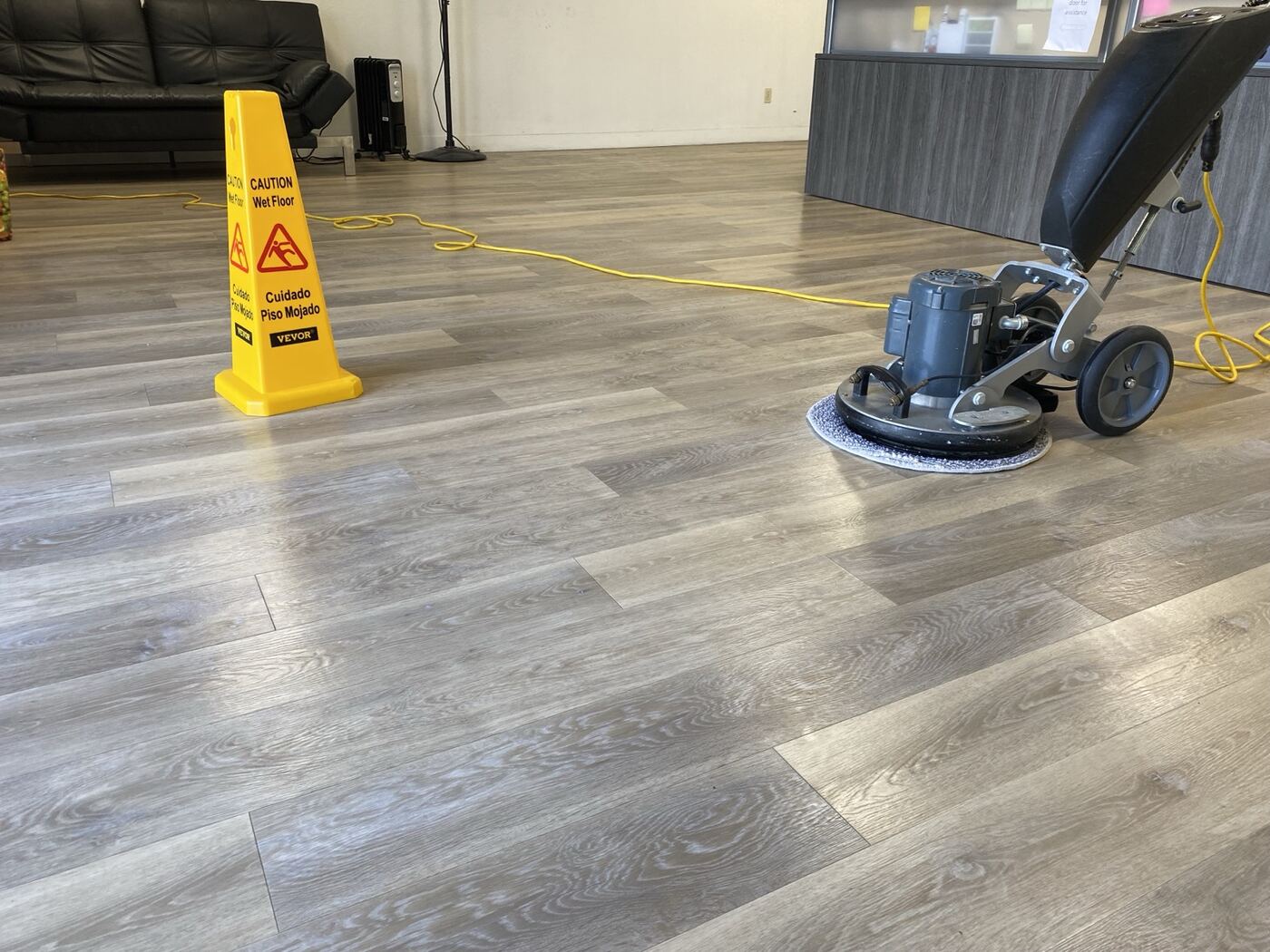 Office lobby floor with buffer and wet-floor cone during Timla service