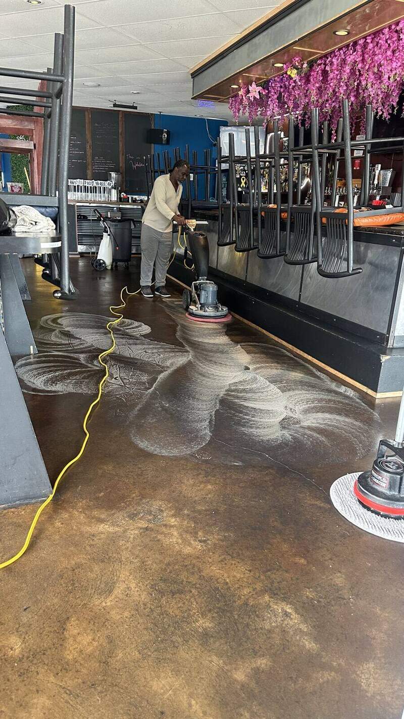 Timla technician scrubbing a restaurant floor with commercial buffer
